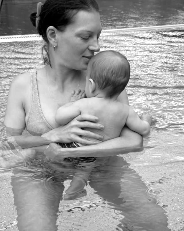 Melanie steht mit ihrem Baby im Arm im Wasser, Schwarzweiß-Aufnahme