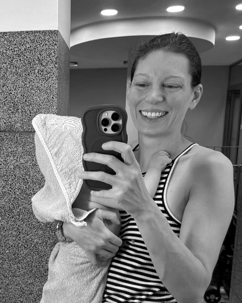Melanie mit ihrem Baby im Kapuzenhandtuch nach dem Schwimmen