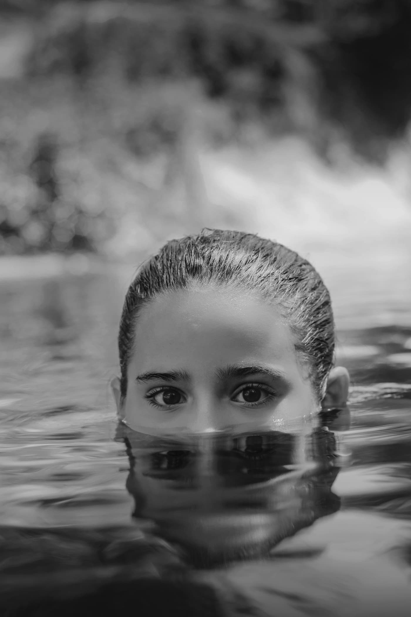 Kindergesicht halb über der Wasseroberfläche, ruhig, in Schwarzweiß